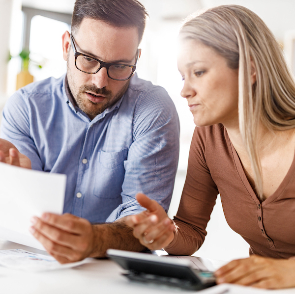 Two people work together while looking at papers and a calculator